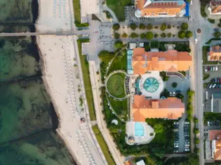 Die Aussicht aus dem A-ROSA Travemünde mit Blick auf den Außenpool, eine Gartenanlage sowie dem Strand mit Strandkörben.