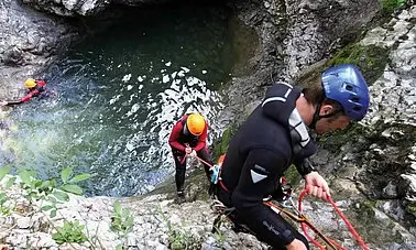 Gruppe von Personen beim Klettern an einer Felswand im Freien.