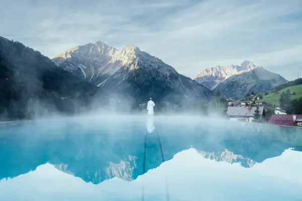 Person am Pool mit Berglandschaft im Hintergrund