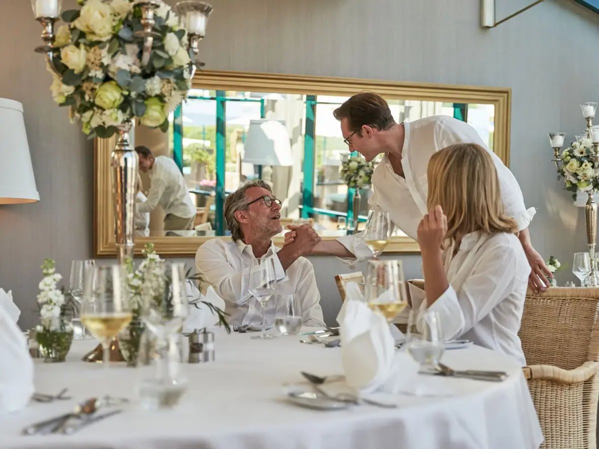 Eine Gruppe von Menschen an einem Tisch mit Blumenarrangements und Geschirr.