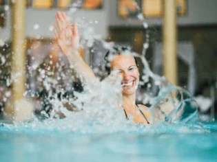 Eine Frau planscht glücklich im Pool