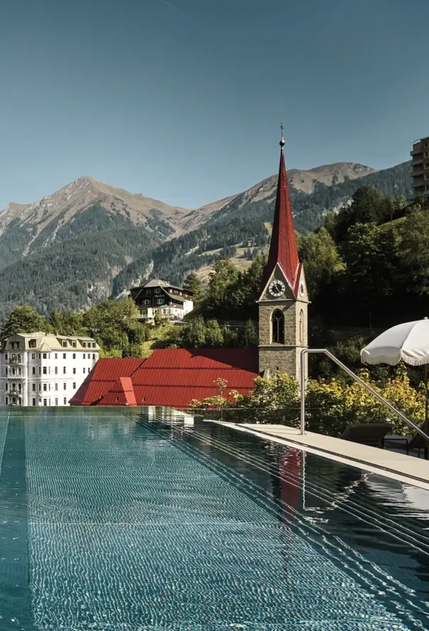 Außenpool vom Straubinger Grand Hotel mit Kirche und Bergen im Hintergrund.