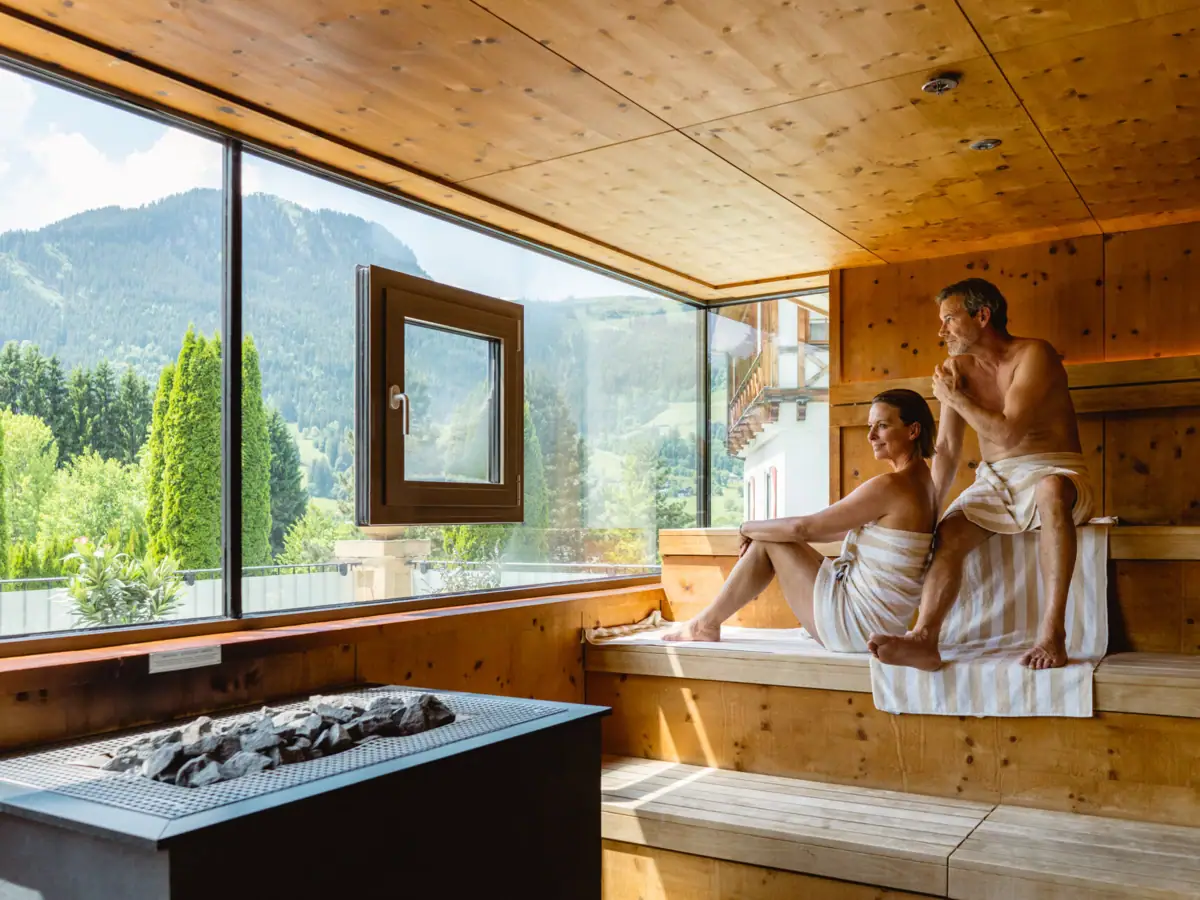 Ein Mann und eine Frau sitzen auf einer Bank in einer Sauna.