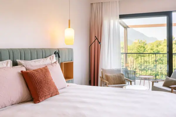 Elegant eingerichtetes Hotelzimmer mit Doppelbett, sanften Farben und Balkon mit Ausblick ins Grüne.