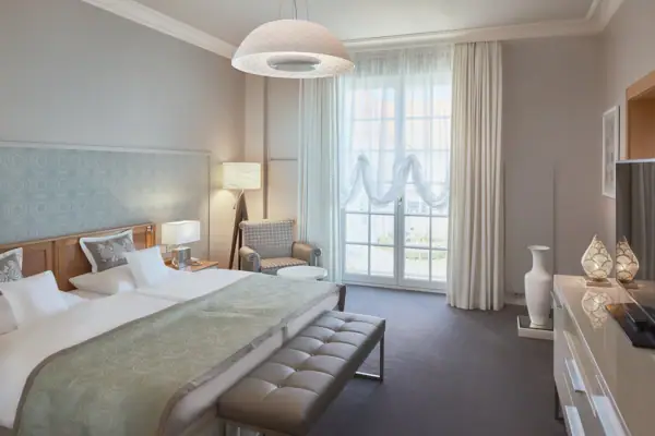 Zimmer Kurhaus Binz Ein Hotelzimmer mit einem Bett und einer Bank.