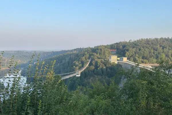 Eine Brücke über einen Fluss mit Himmel und Bäumen im Hintergrund.