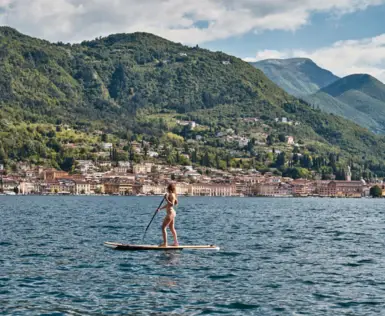 Frau auf einem Paddleboard auf dem Wasser mit einer Stadt im Hintergrund.