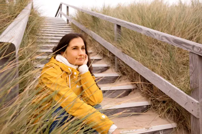 A-ROSA Sylt Strand Frau Eine Frau sitzt auf Treppen und stützt ihr Kinn mit der Hand.