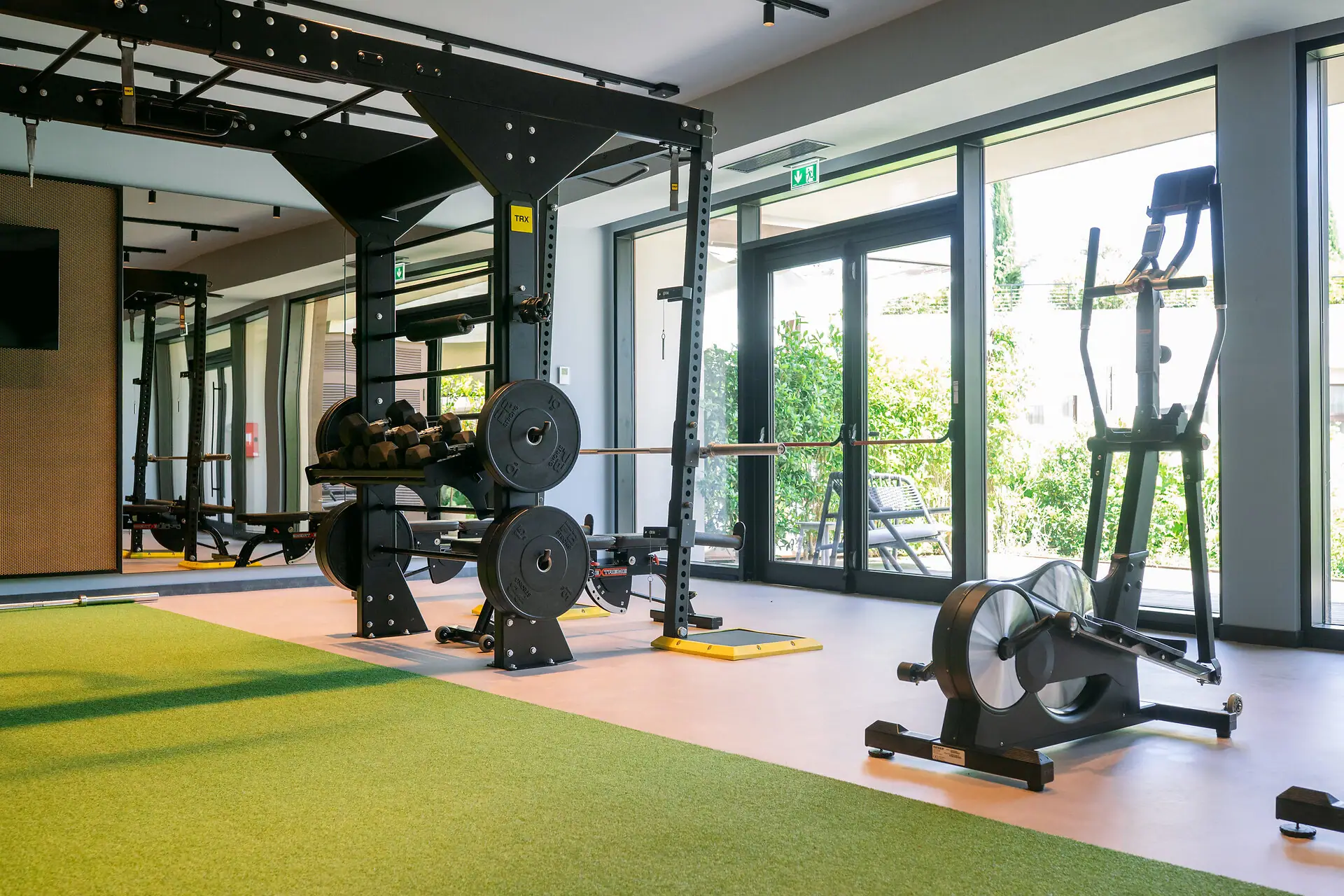 Cardio-Geräte wie Ergometer im Fitnessraum des A-ROSA Gardasee mit Blick ins Grüne.