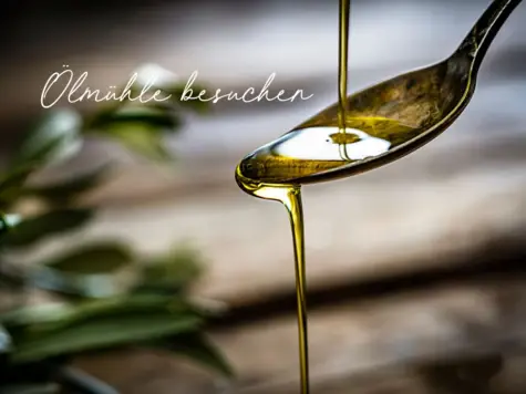 Ein Löffel, auf dem Olivenöl fließt und im Hintergrund ist ein Holztisch mit Olivenblättern zu erkennen.