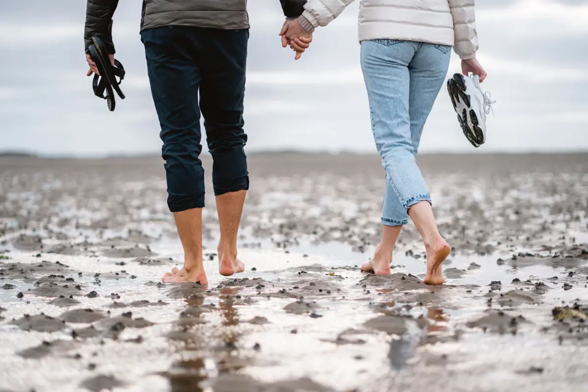 Wattwanderung Sylt Ein Mann und eine Frau halten Händchen und machen eine Wattwanderung auf Sylt.