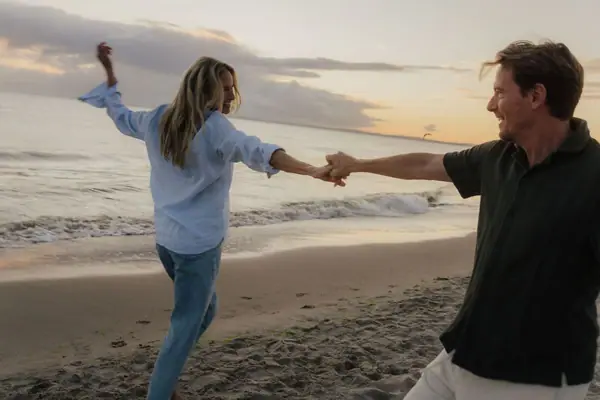 Ein Mann und eine Frau halten sich an einem Strand an den Händen.