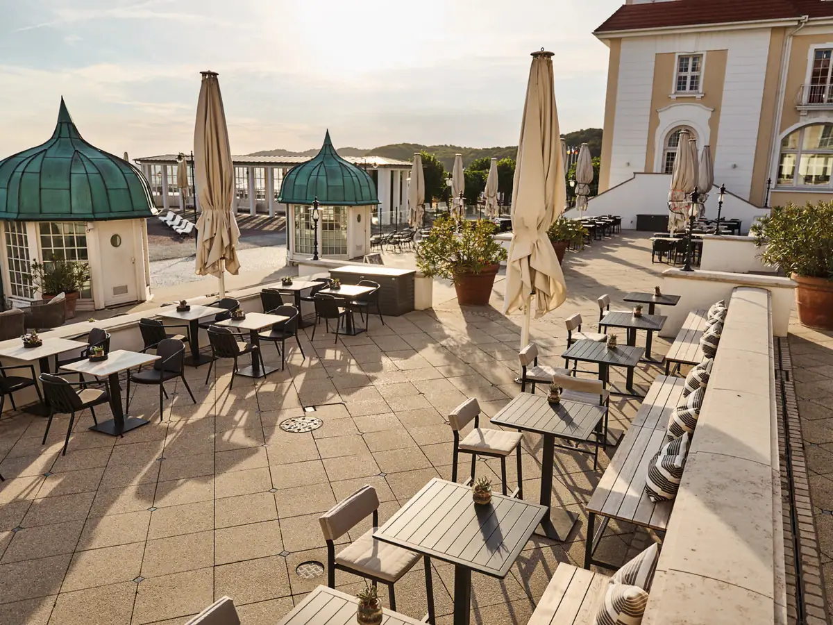Eine Terrasse mit Tischen und Sonnenschirmen.