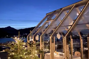 Tegernsee Weihnachten Ein Glashaus mit einem Baum und Lichtern bei Nacht.