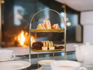 A tray of food on a table with various dishware including a coffee cup, saucer, plate, and teapot.