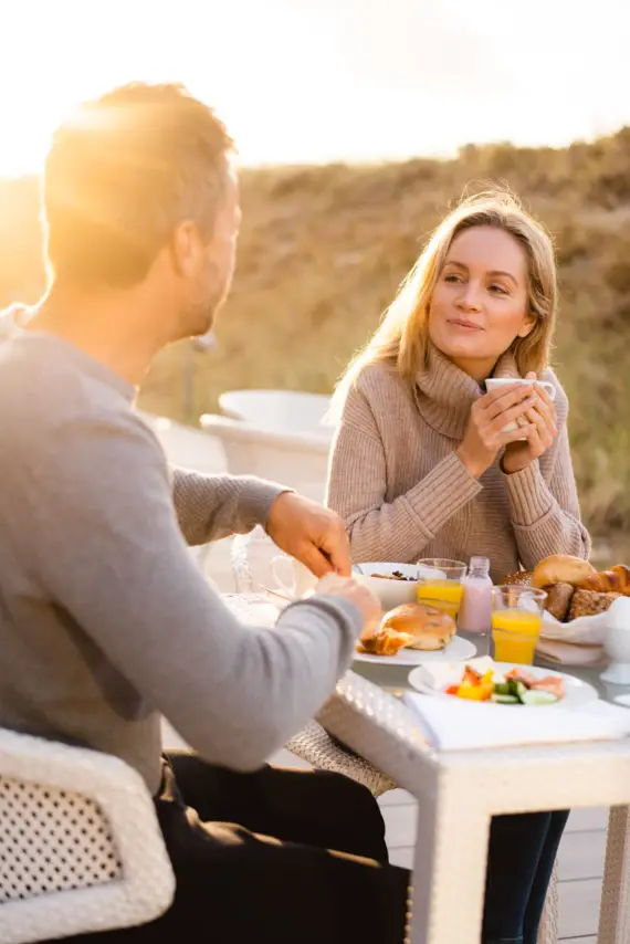 Ein Mann und eine Frau sitzen draußen an einem Tisch und essen.