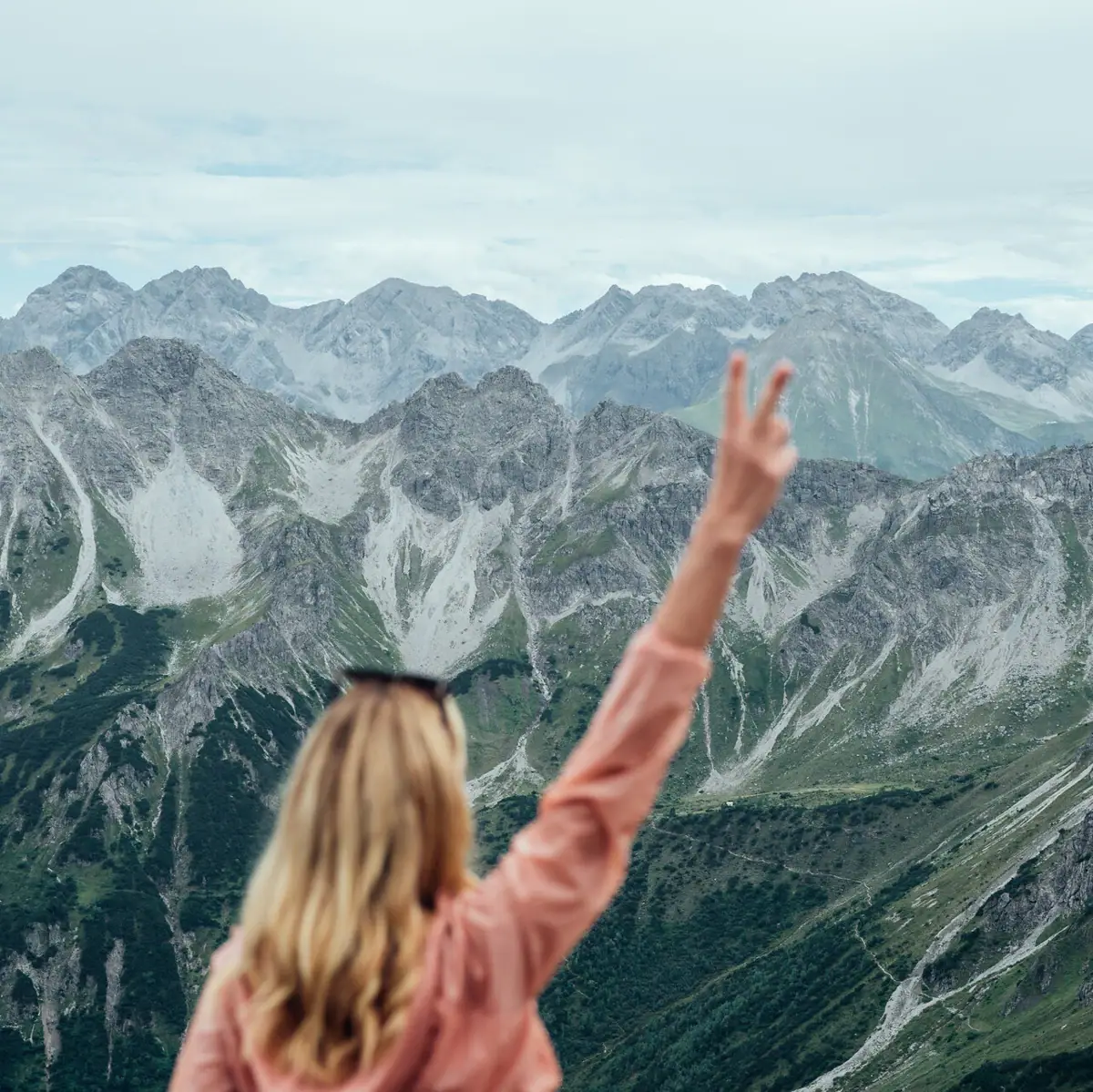 Eine Frau steht auf einem Berg mit erhobener Hand.