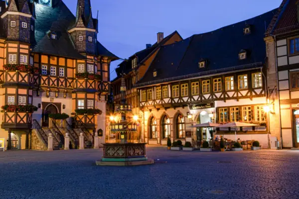 Ein Fachwerkgebäude mit einem Brunnen davor.