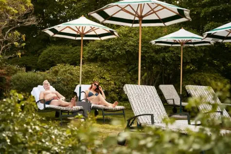 A man and a woman sit on deckchairs under parasols.