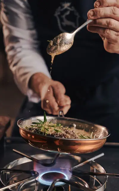 Person seasons food in a pan.