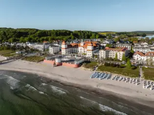 Strand mit großem Gebäude und Stühlen darauf.