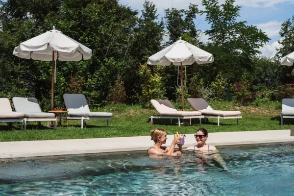 Zwei Gäste stoßen im Pool des A-ROSA Gardasee mit Getränken an