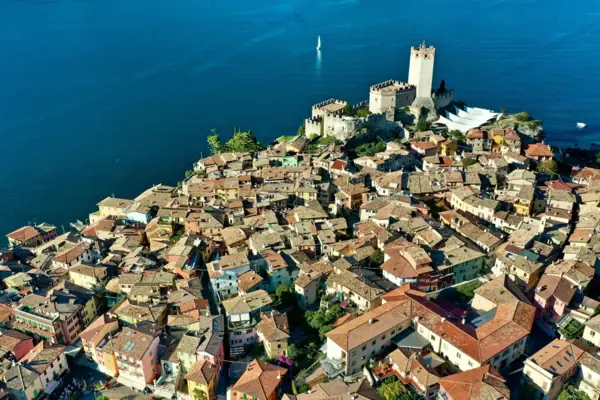 Luftaufnahme einer Stadt mit einem Schloss am Rand, umgeben von Wasser.