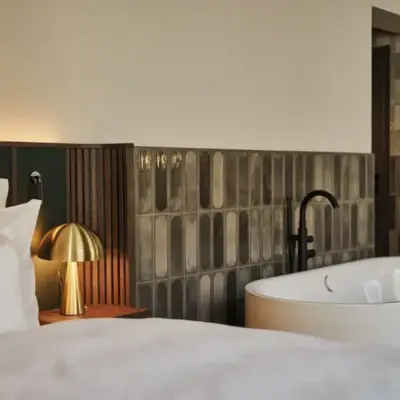 Ein Anschnitt eines Bettes sowie einer freistehenden Badewanne