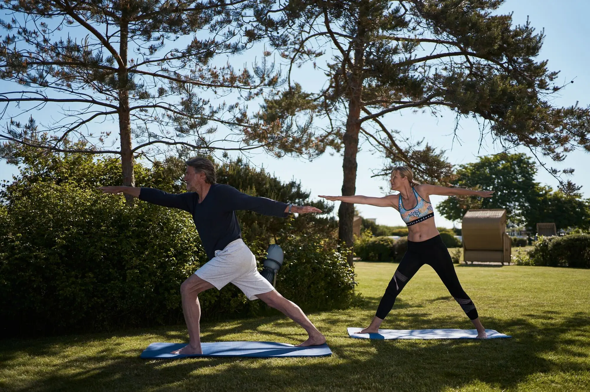 Ein Mann und eine Frau machen Yoga auf dem Rasen.