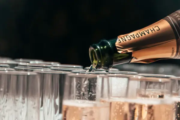 Eine Champagnerflasche schenkt Champagner in eine Vielzahl an Gläsern ein. 