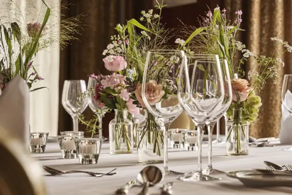 Ein Tisch dekoriert mit Blumen und Kerzen in Vasen.