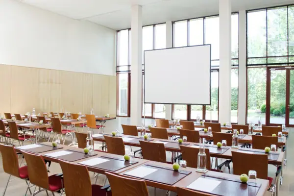 Ein moderner, lichtdurchfluteter Tagungsraum mit Tischen und Stühlen.