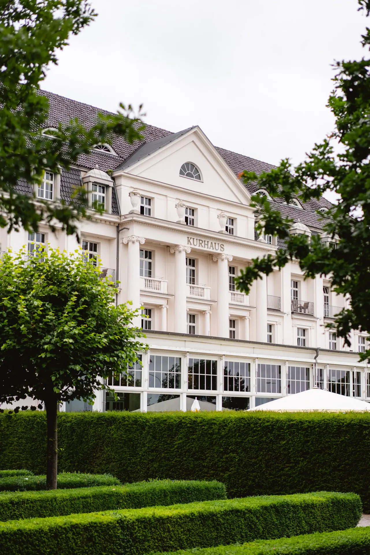 Weißes Gebäude mit Bäumen im Hintergrund