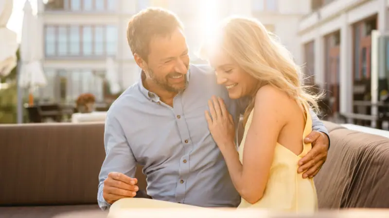 Ein Mann und eine Frau sitzen lächelnd auf einem Sofa.