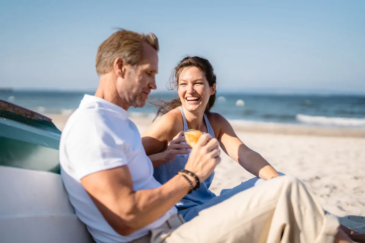 Ein Mann und eine Frau sitzen am Strand.