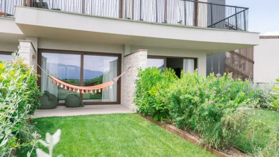 Hammock in front of a house with a porch and grassy yard.