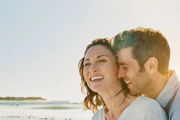 Ein Mann und eine Frau umarmen sich am Strand.