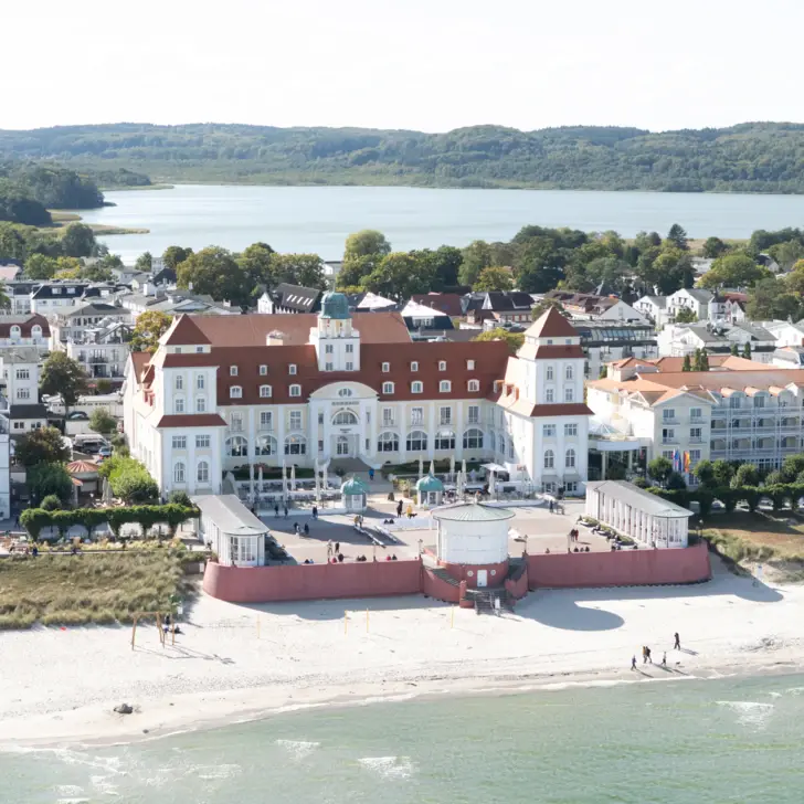 Swimmingpool im Freien umgeben von Stühlen und Sonnenschirmen mit Bäumen und einem klaren Himmel mit untergehender Sonne im Hintergrund.