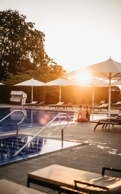 Hotel-Pool mit Liegen und Sonnenschirmen im Sonnenuntergang
