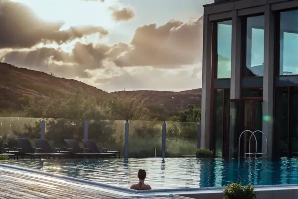 Eine Frau im Schwimmbecken mit einem Gebäude im Hintergrund.