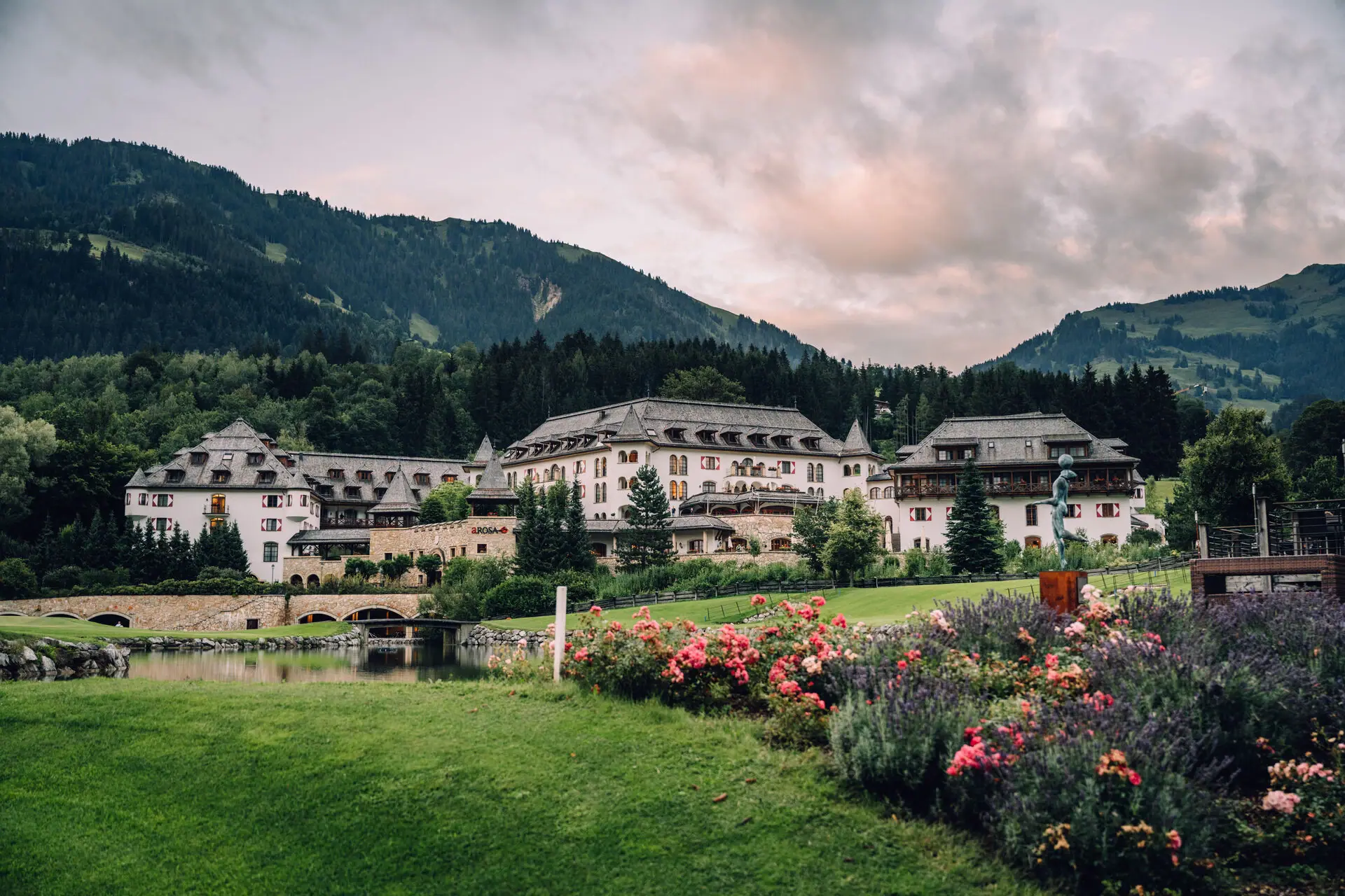 Großes Gebäude mit Garten und See im Vordergrund.