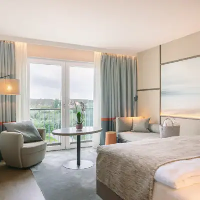 Zimmer mit Bett, Tisch und Stühlen.