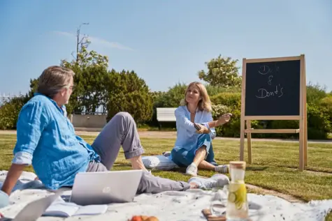 Mann und Frau sitzen auf einer Wiese im Park.