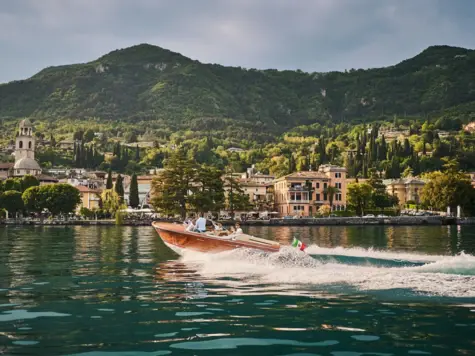 Boot auf dem Gardasee umgeben von Bergen und Wolken.