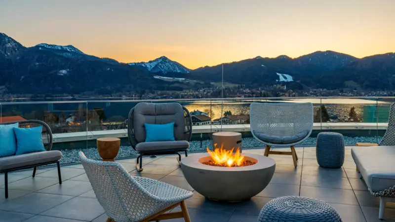 Rooftop Bar mit Feuerstelle mit Stühlen und Blick auf Berge im Hintergrund