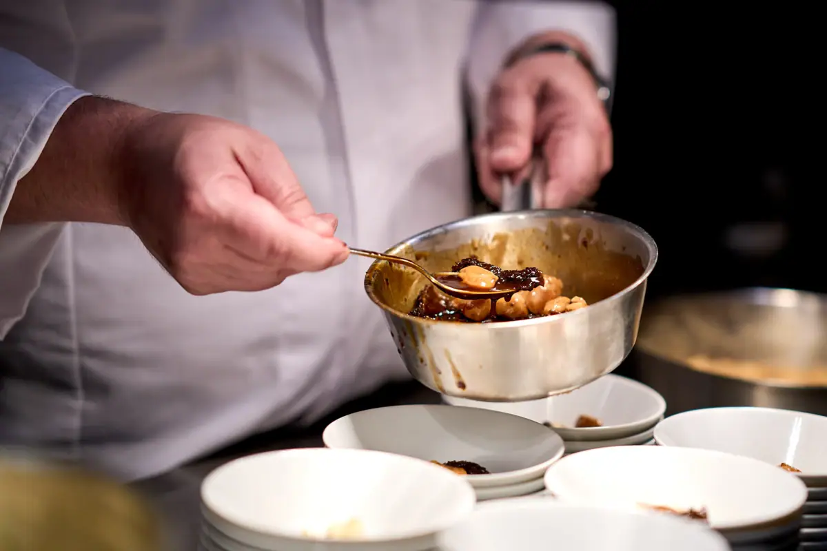 Eine Person hält einen Löffel über eine Schüssel mit Essen.