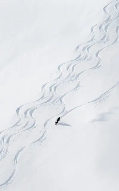 Person beim Skifahren auf verschneiter Piste in einem Skiort.