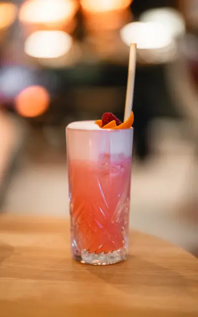 Ein Glas mit einem rosa Getränk und einem Strohhalm.
