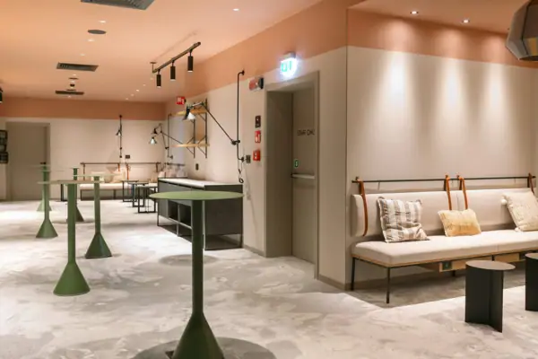 Ein Raum mit einer Couch und Tischen. Es gibt verschiedene Stehtische, die sich für einen Empfang eignen.