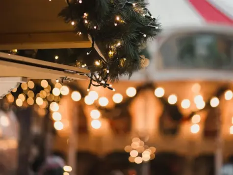 Weihnachtsgirlande auf einem Dach, geschmückt mit Lichtern und Christbaumschmuck.